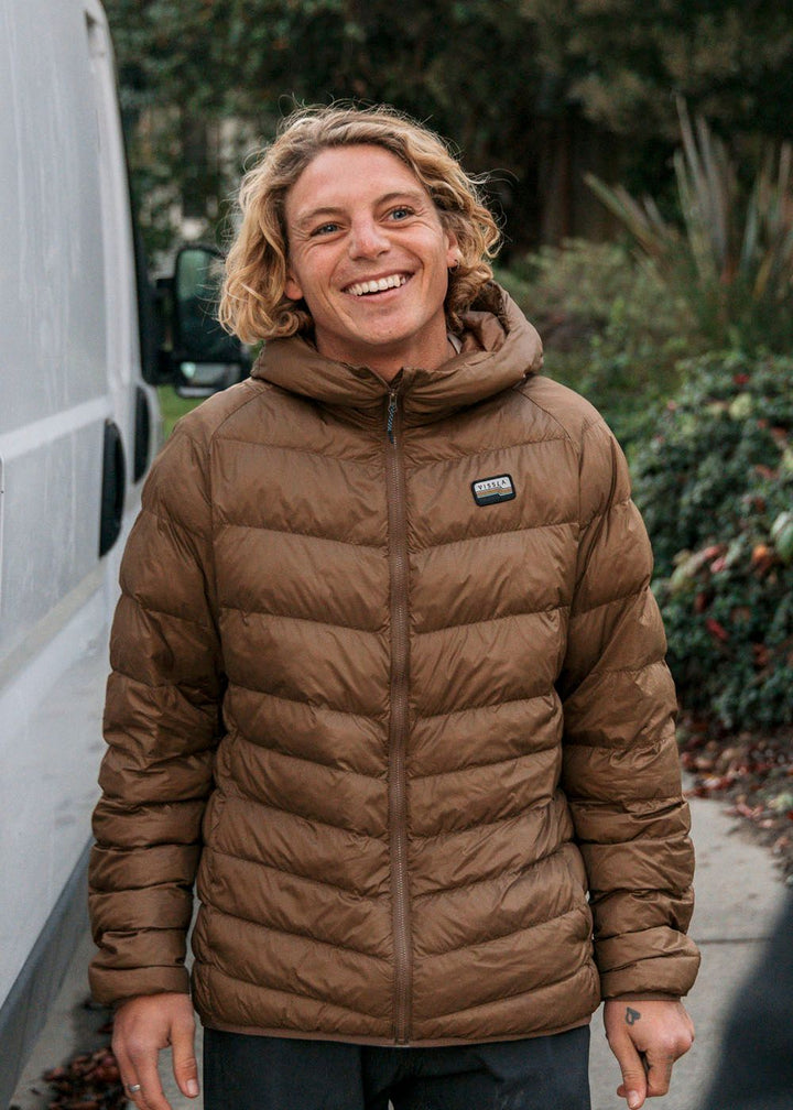 Person wearing Vissla Pacific Packable Eco Puff Jacket in brown outdoors.